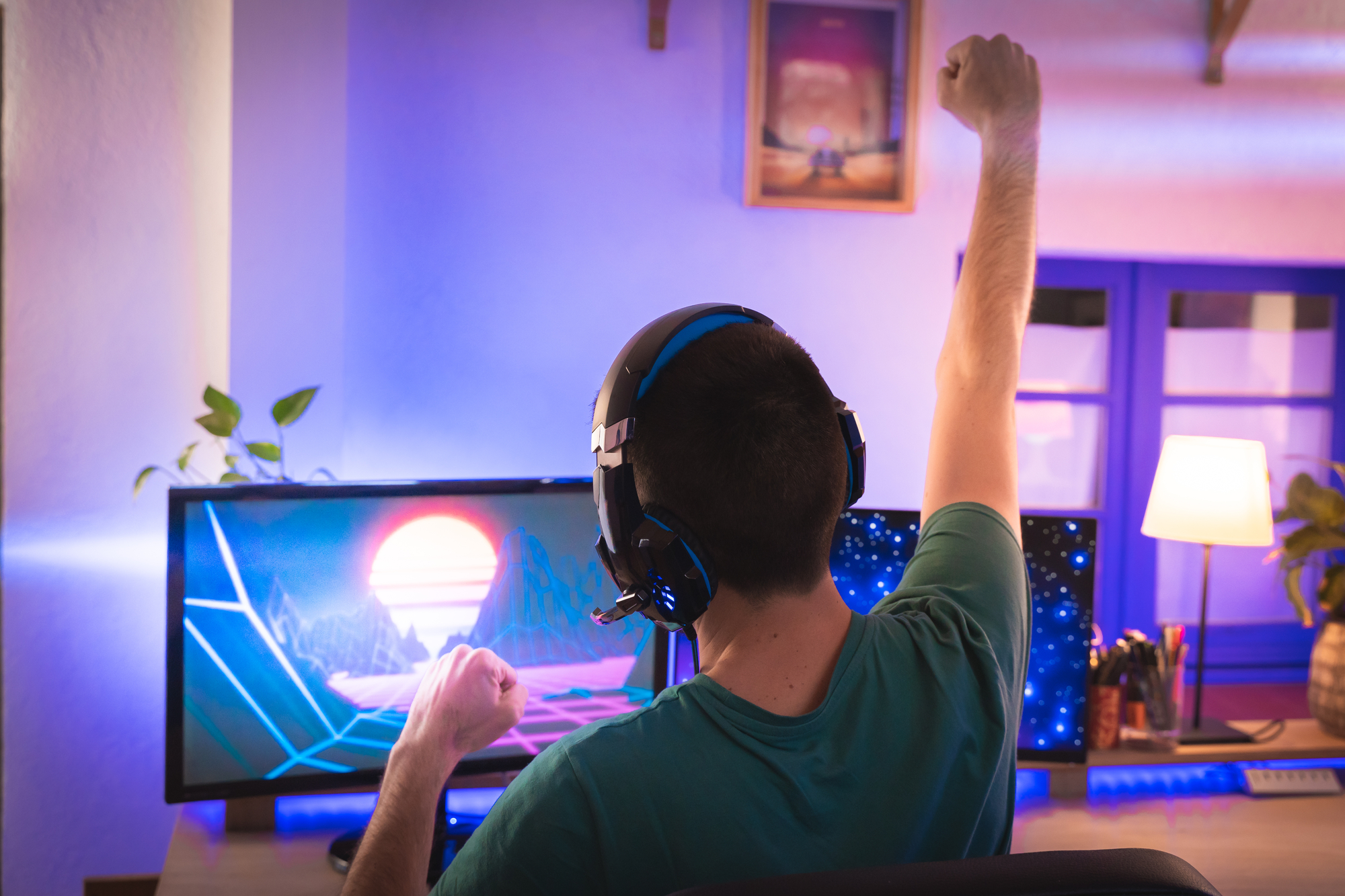 A man is playing a game on his computer while learning how to make money off Steam. One fist held in the air triumphantly