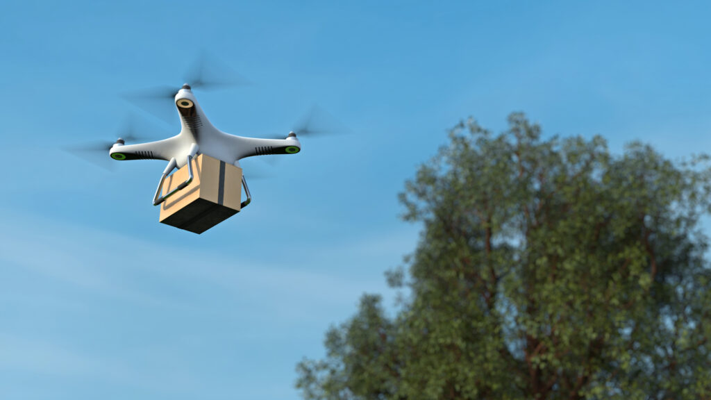 A drone flies over a box with a tree in the background.