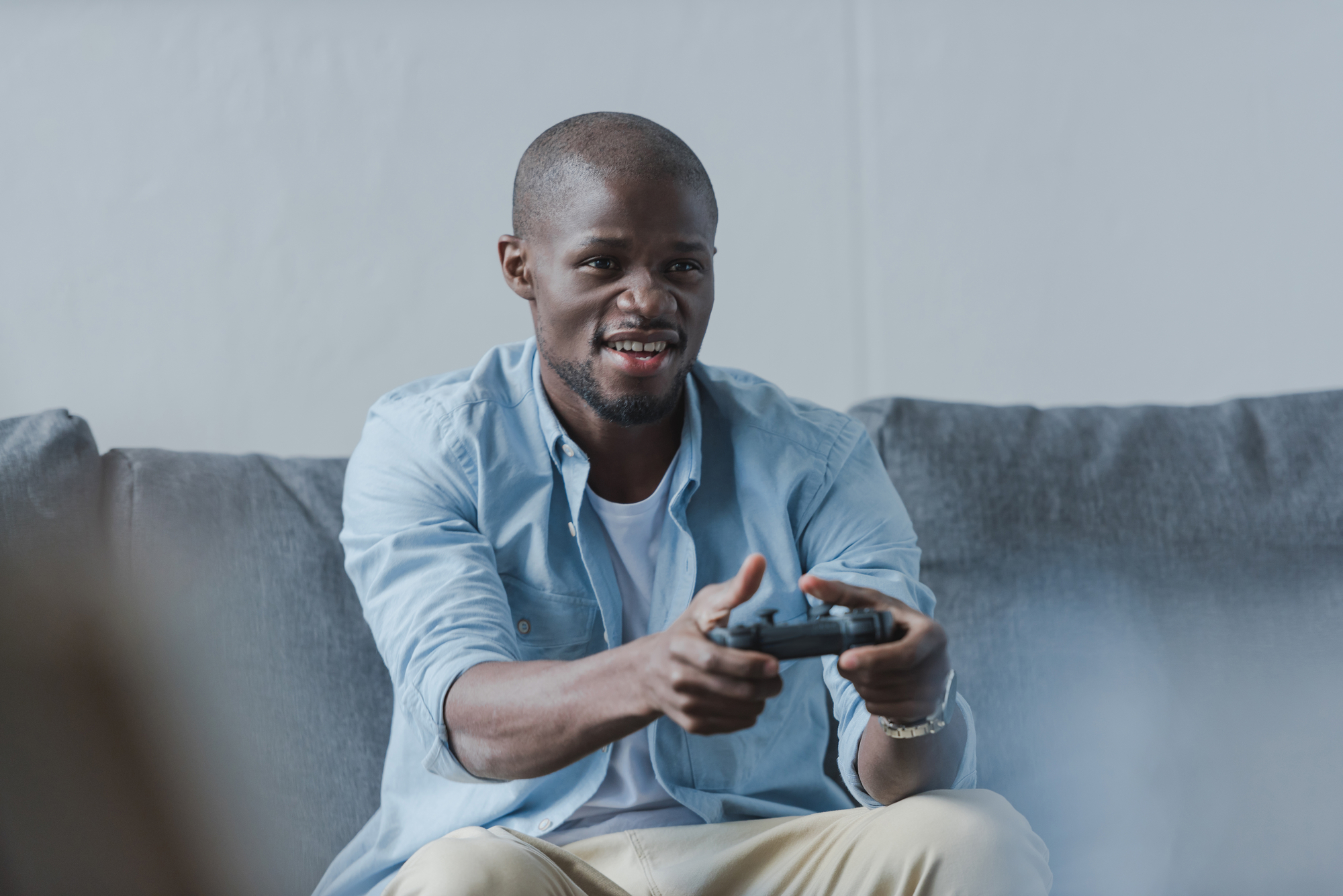A man sitting on a couch, getting paid to play video games with the controller in his hand.