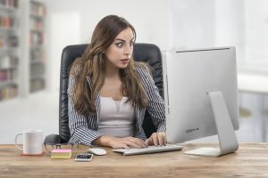 Young woman looking at her computer with a shocked expression, perhaps receiving the dreaded matched betting gubbing email!