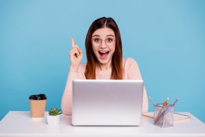 A woman at a desk with a laptop shares matched betting tips while pointing her finger upwards.