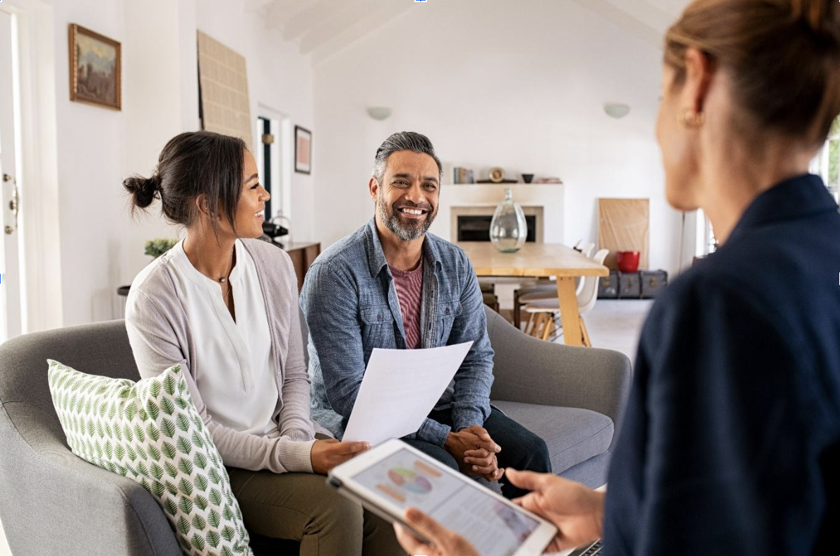 A conversation on a couch between two people and a real estate agent discussing the benefits of wealth management services for retirement.