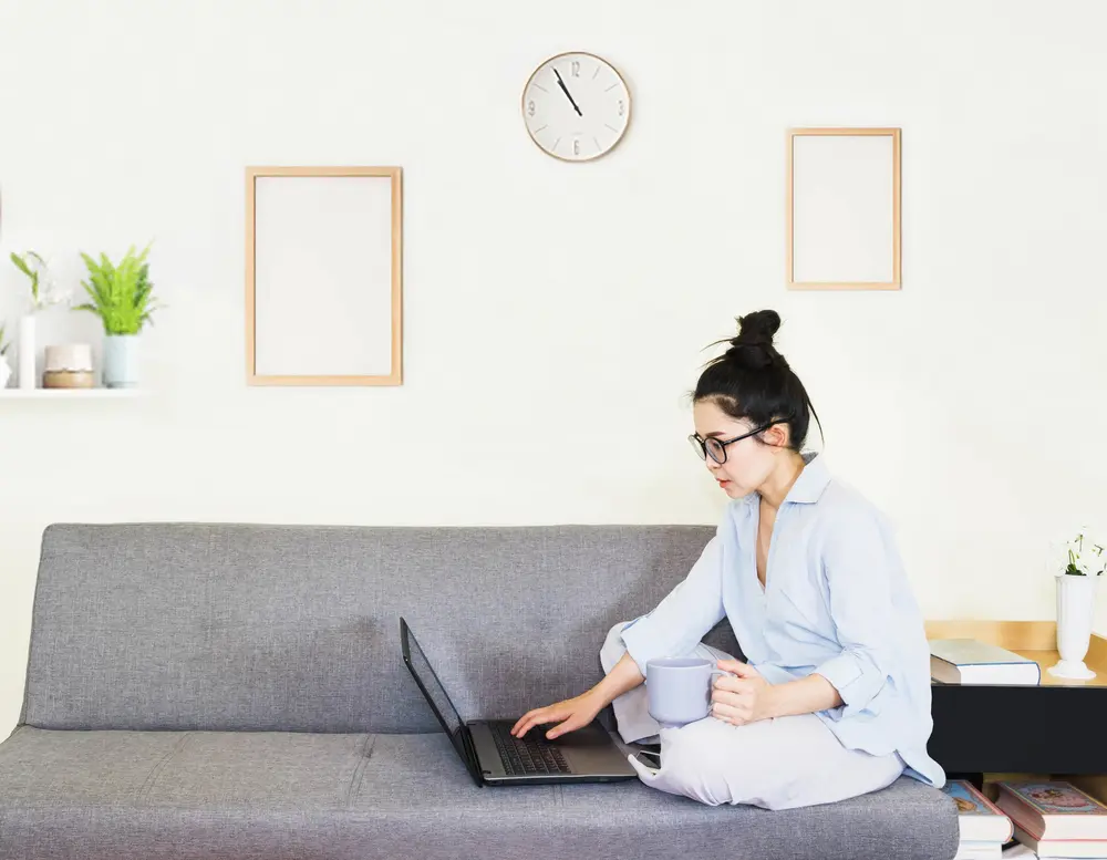 A woman sitting on her sofa using her laptop