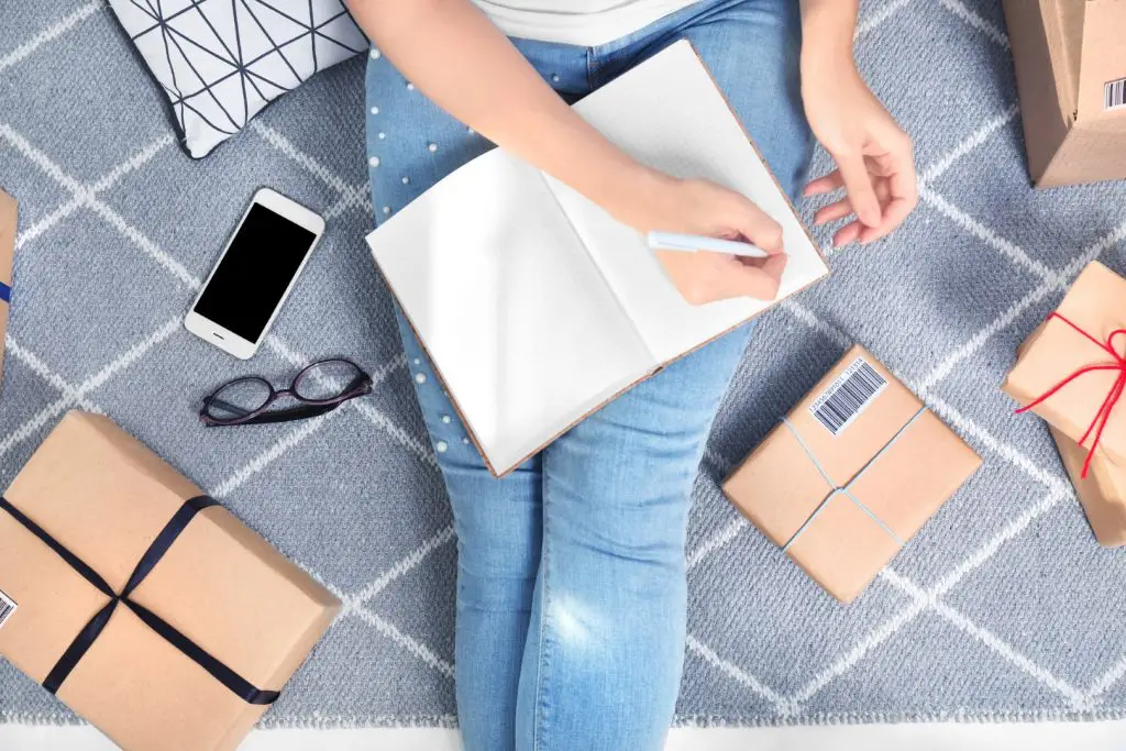 An Amazon FBA seller with a notepad surrounded by boxes to ship