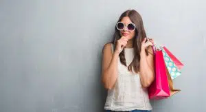 a young brunette mystery shopper holding shopping bags and wearing sunglasses