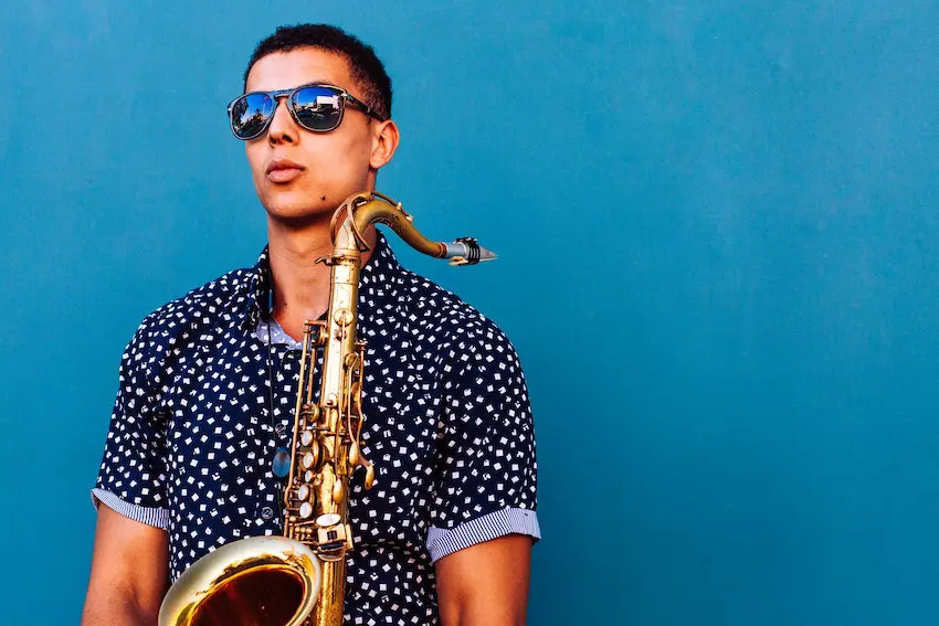 a street musician holding a saxophone against a blue background.