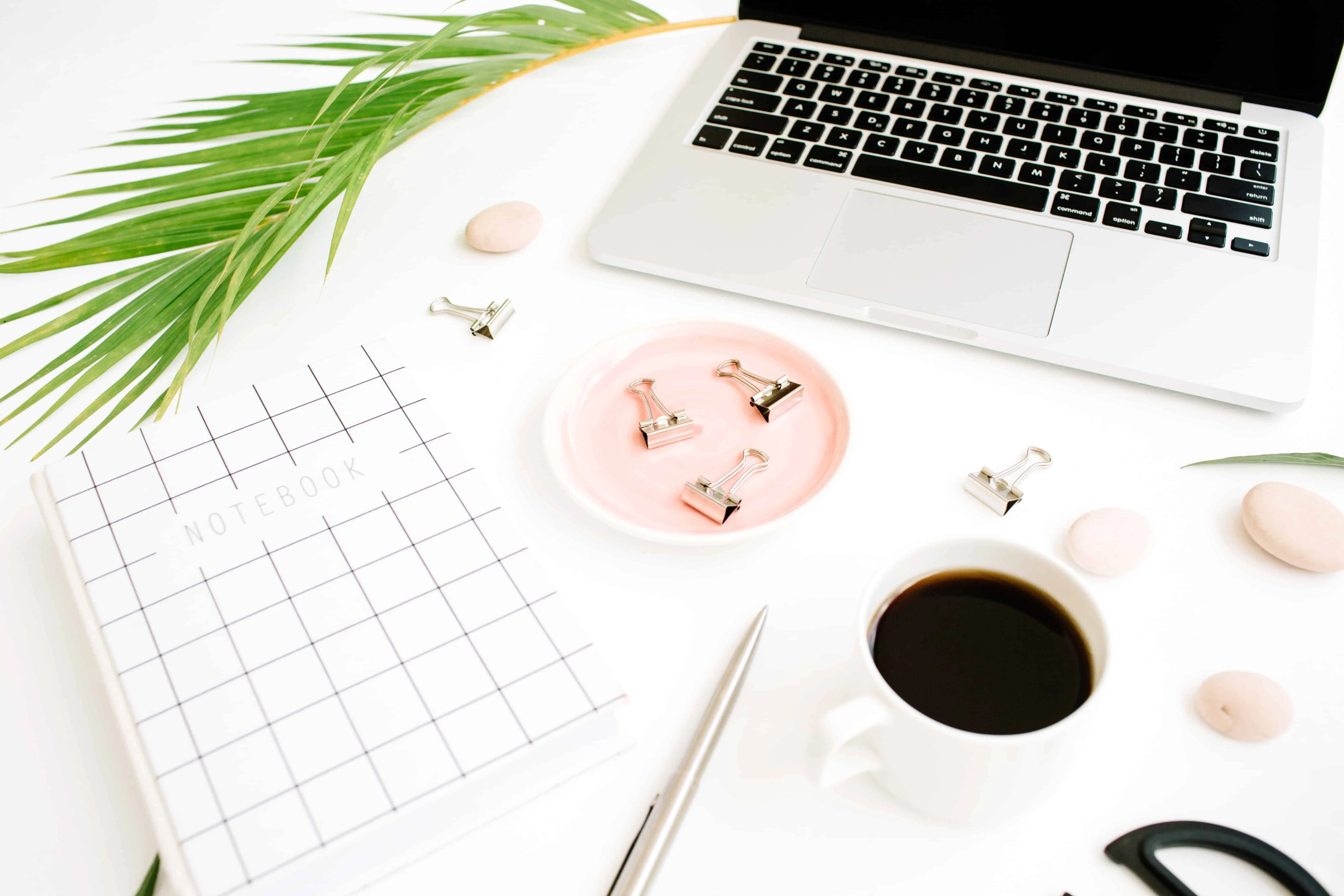 a blogger workspace flat lay with laptop, coffee and notebook