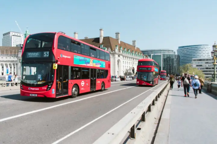 London buses on a street. One way to make money on Airbnb without owning a property is by offering guided tours of your city on Airbnb Experiences.