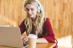 A transcriber working with headphones, laptop and coffee